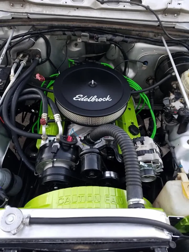 A freshly detailed engine bay with a lime green block, chrome air cleaner, and new green plug wires